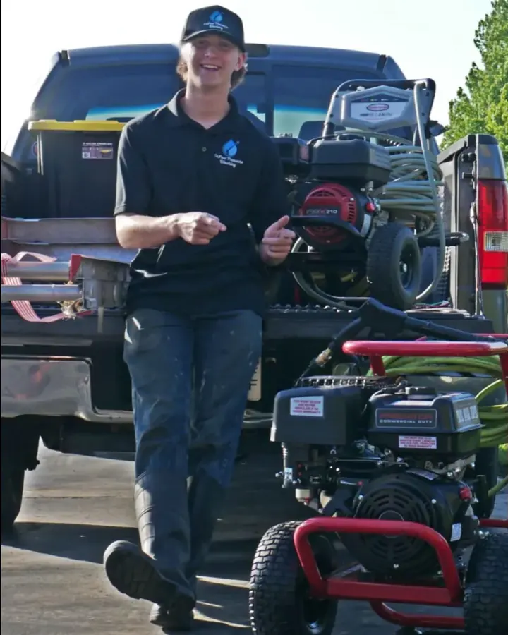 Caleb standing beside his black truck with two pressure washers
