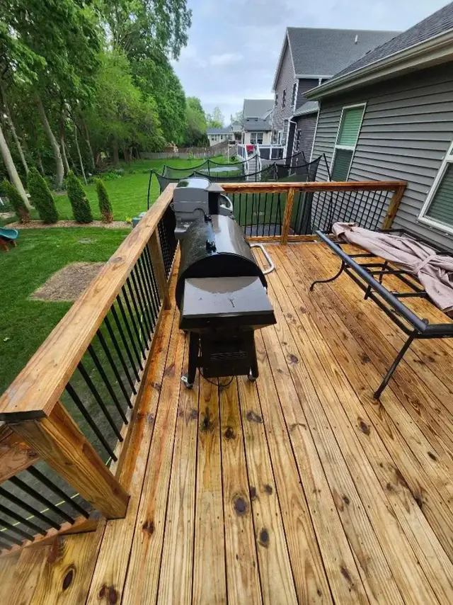 Clean wooden deck boards with a railing and a green yard behind