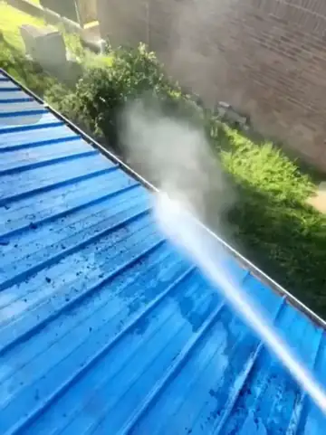 Water spraying in a wide fan across a blue metal roof