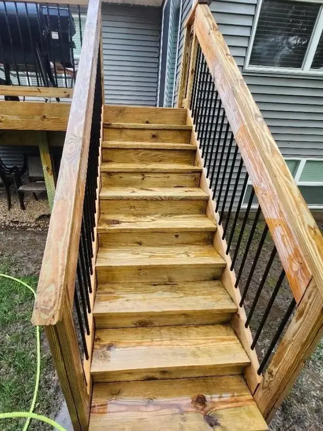 Clean wooden deck stairs with black metal railings